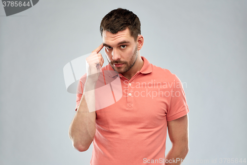 Image of man with finger at temple over gray background