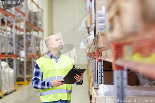 Image of man with clipboard in safety vest at warehouse