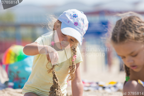 Image of Four-year girl builds a sand castle on the beach