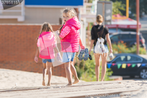 Image of Mother and two daughters are on the wooden flooring in the sand, one girl turned