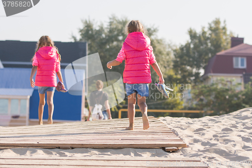 Image of Two daughters go home for his mother on the wooden flooring in the sand