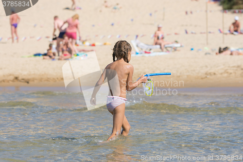 Image of girl out of the water while holding the mask and a swimming tube in his hands