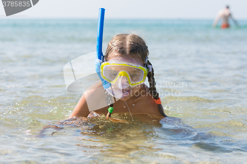 Image of The girl emerged from the water with a mask on his face and respiratory tube smiling and looking into the frame