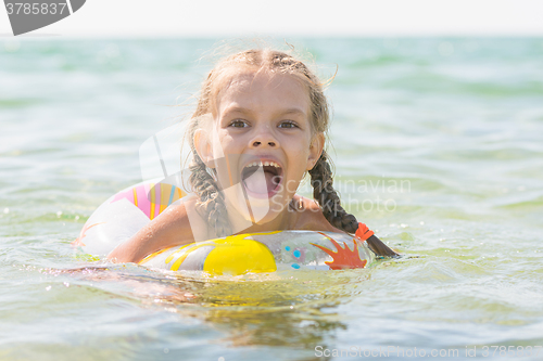 Image of Six year old girl bathing in the sea with his mouth open in pleasure