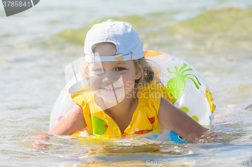 Image of Four-year girl swims in the summer with a circle in the sea