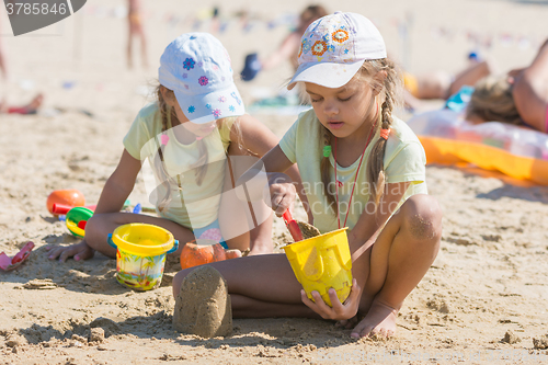 Image of Two girls playing in the sand on the beach