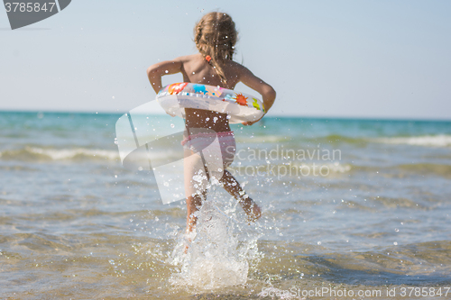 Image of Girl runs to bathe in the sea, focus on a spray of water