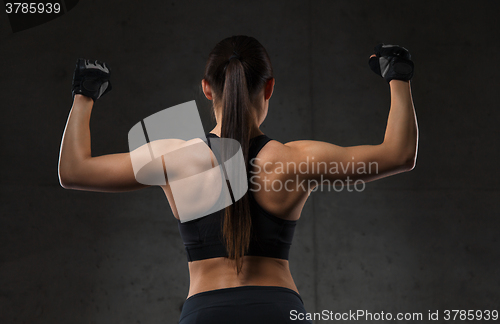 Image of young woman flexing muscles in gym