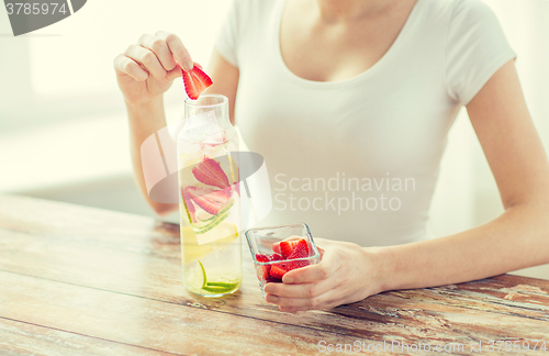 Image of close up of woman with fruit water in glass bottle