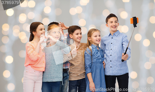 Image of happy children with smartphone and selfie stick