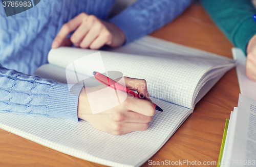 Image of close up of student hands writing to notebook