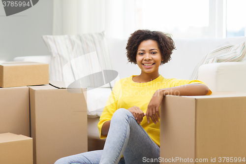 Image of happy african woman with cardboard boxes at home
