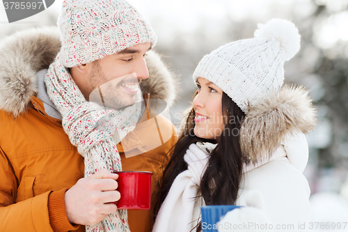 Image of happy couple with tea cups over winter landscape