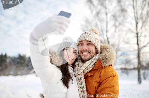 Image of happy couple taking selfie by smartphone in winter
