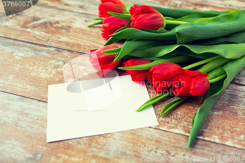 Image of close up of red tulips and blank paper or letter