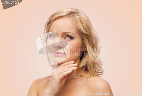Image of smiling woman with bare shoulders touching face