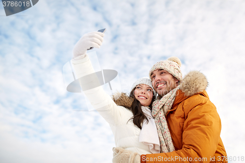 Image of happy couple taking selfie by smartphone in winter