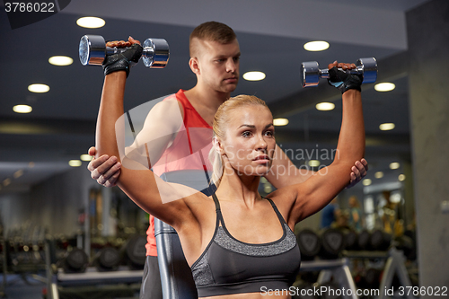 Image of man and woman with dumbbells in gym