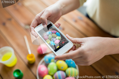 Image of close up of hands with easter eggs and smartphone