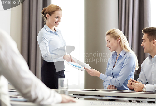 Image of woman giving papers to group of businessmen