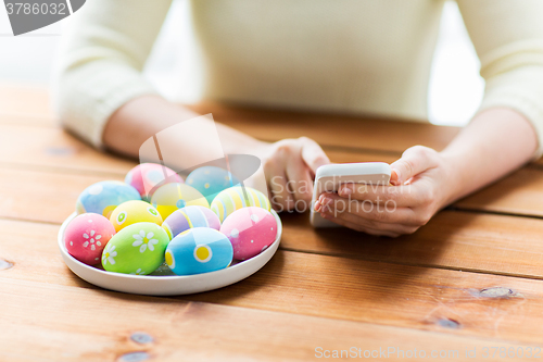 Image of close up of hands with easter eggs and smartphone