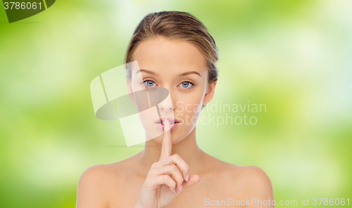 Image of beautiful young woman holding finger on lips