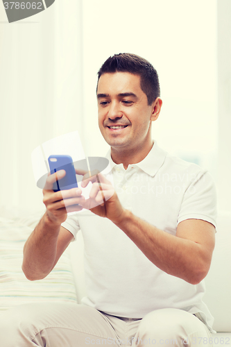 Image of happy man with smartphone at home