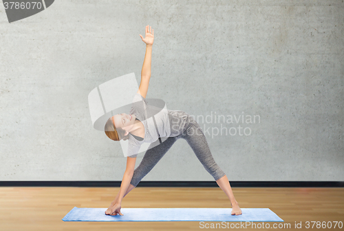 Image of woman making yoga triangle pose on mat