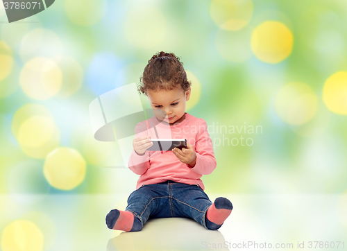 Image of smiling little baby girl playing with smartphone