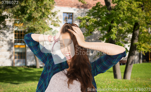 Image of happy pretty teenage student girl holding to head