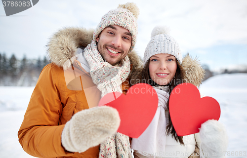 Image of happy couple with red hearts over winter landscape