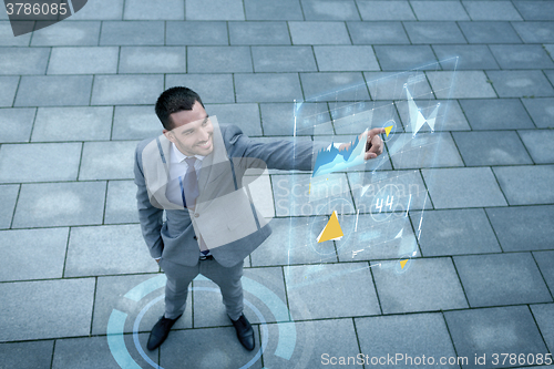 Image of smiling businessman with virtual screens outdoors