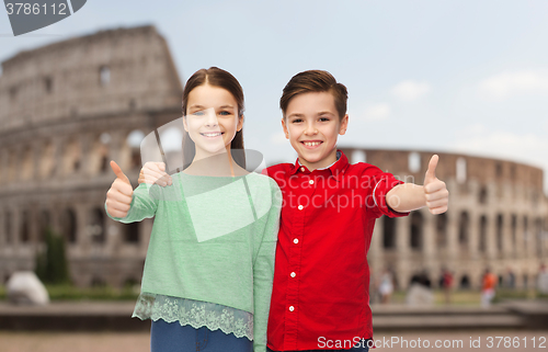 Image of happy boy and girl showing thumbs up over coliseum