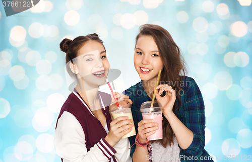 Image of happy pretty teenage girls drinking milk shakes