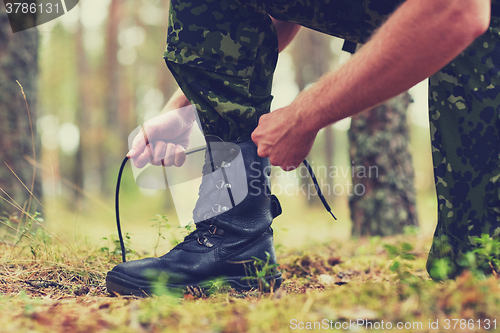 Image of close up of soldier tying bootlaces in forest