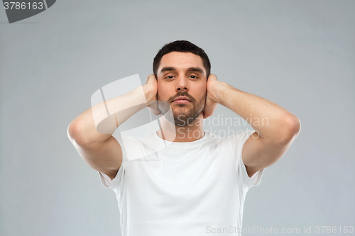 Image of latin man covering his ears with hand palms