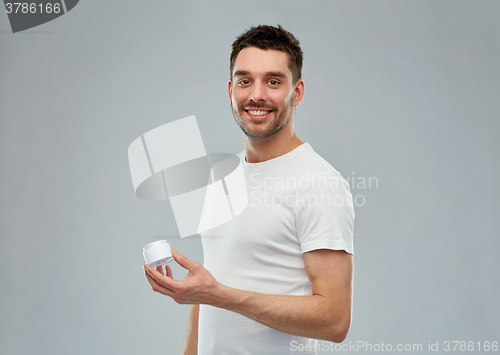 Image of happy young man with cream jar over gray