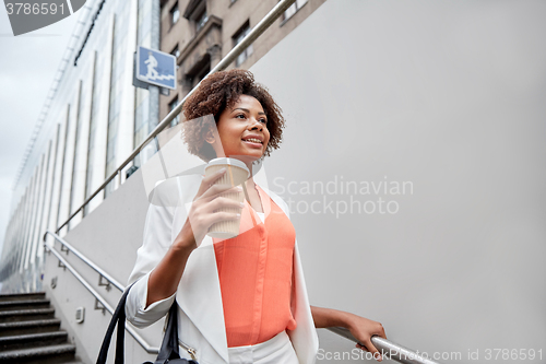 Image of happy african businesswoman with coffee in city