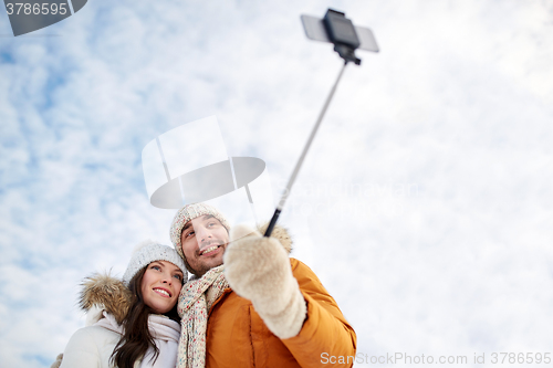 Image of happy couple taking selfie by smartphone in winter