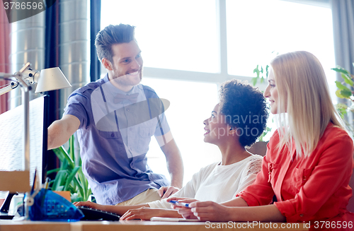 Image of happy creative team with computer in office
