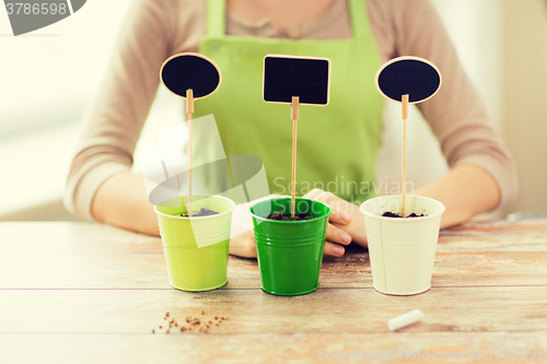 Image of close up of woman over pots with soil and signs