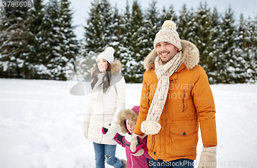 Image of happy family in winter clothes walking outdoors