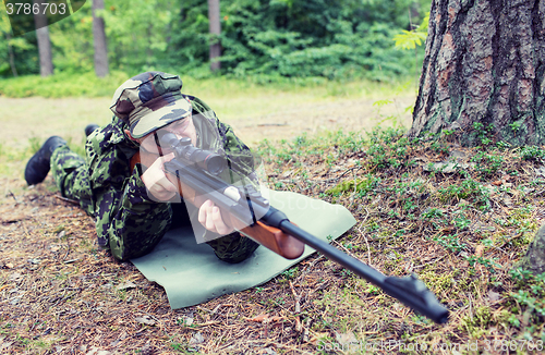 Image of young soldier or hunter with gun in forest