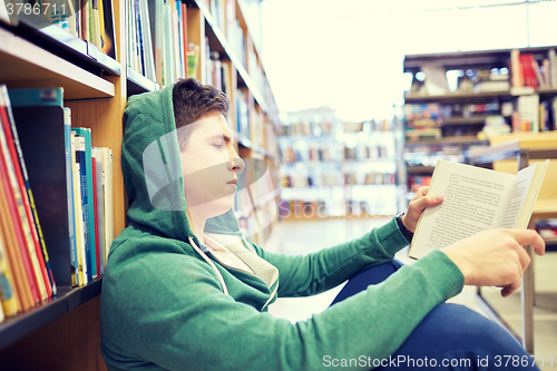 Image of student boy or young man reading book in library