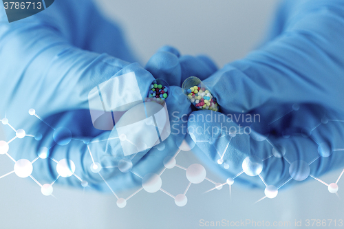 Image of close up of scientist hands holding pill in lab