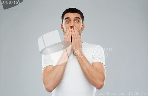 Image of scared man in white t-shirt over gray background