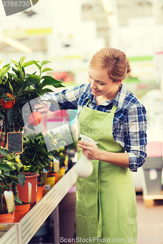 Image of happy woman touching mandarin tree in greenhouse