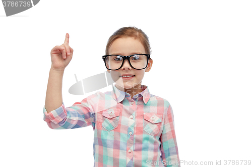 Image of happy little girl in eyeglasses pointing finger up