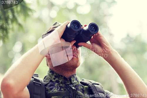 Image of young soldier or hunter with binocular in forest