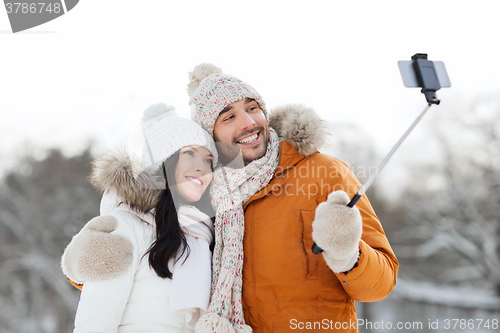 Image of happy couple taking selfie by smartphone in winter